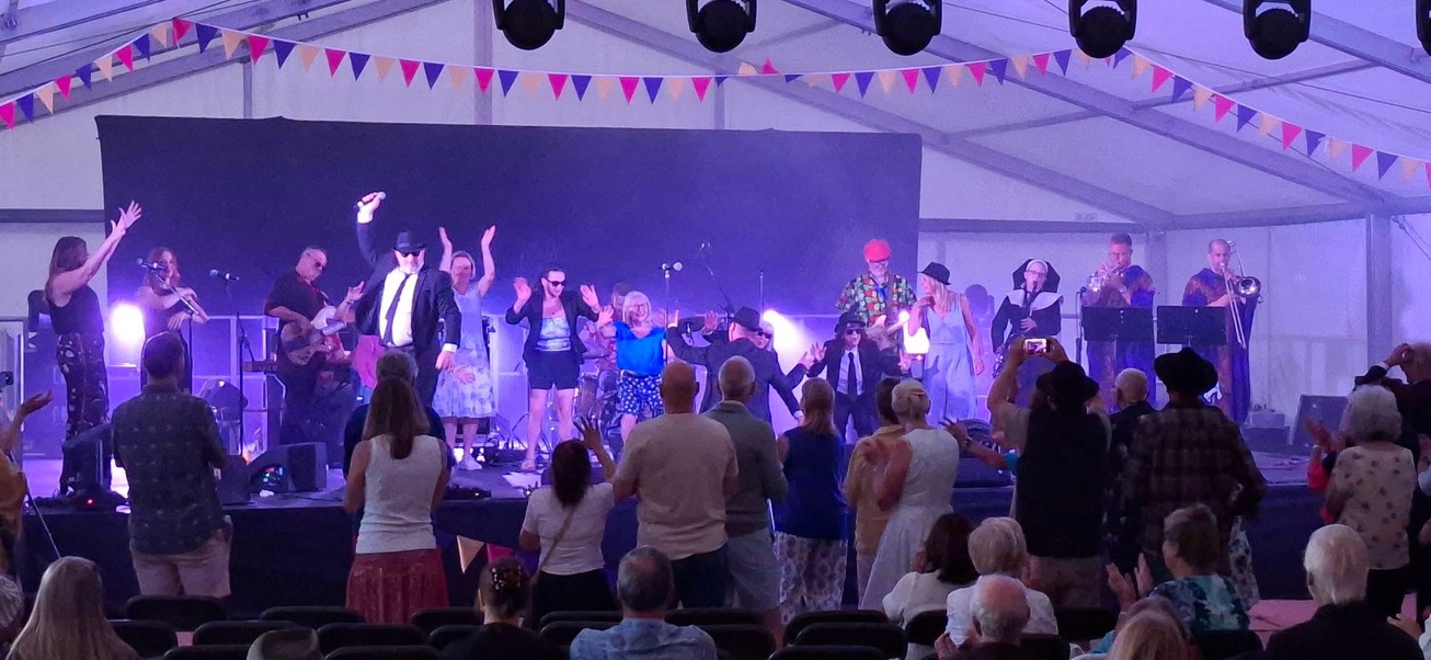 Festival audience members dancing on stage with the 11-piece band